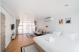 a bedroom with a large white bed and a living room at Mitt Haus (Lat Phrao Soi 5) in Bang Su
