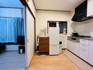 uma cozinha com um frigorífico e um micro-ondas em ZYZ Showamachi-house em Tóquio