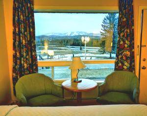 a room with a bed and two chairs and a window at Motel Tremblant in Mont-Tremblant