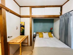 um pequeno quarto com uma cama e uma secretária de madeira em ZYZ Showamachi-house em Tóquio