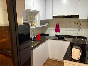 a kitchen with white cabinets and black counter tops at Kuching City Center Riverbank Suites With Marvelous River View in Kuching