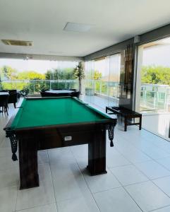 a pool table in a large room with windows at Aguas do Santinho Residence - Praia do Santinho in Florianópolis