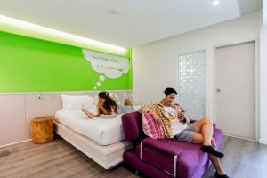 a man and woman sitting on a bed in a bedroom at The Tint At Phuket Town - SHA Plus in Phuket Town