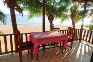 - une table et des chaises sur une terrasse couverte donnant sur la plage dans l'établissement The Scenery Beach Resort, à Baan Khai
