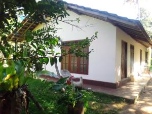 a small white house with a window and a yard at Sugaya in Matara