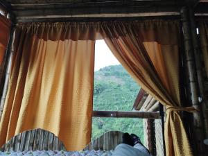 a person laying on a bed looking out a window at La Cabaña de Bambú in Manizales
