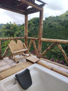 une baignoire assise à côté de deux chaises sur une terrasse dans l'établissement La Cabaña de Bambú, à Manizales