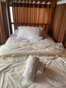 Kelingking Hostel في Klungkung: سرير عليه شراشف بيضاء وزهور