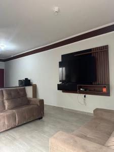 uma sala de estar com um sofá e uma televisão de ecrã plano em Casa na Praia com Piscina - Mongaguá - Drake House em Mongaguá