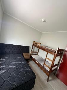 een slaapkamer met een bed, een stapelbed en een ladder bij Casa na Praia com Piscina - Mongaguá - Drake House in Mongaguá