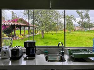 encimera de cocina con fregadero y ventana en Room in Bungalow - Grandfathers Farm - Disfruta de la naturaleza en un lindo flat, en Cajamarca