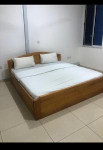 a bed in a room with a wooden frame and pillows at WILLS COURT in Accra