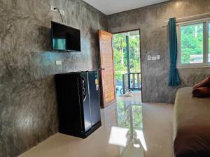a kitchen with a refrigerator and a tv on a wall at Baanchomjan Kohyaoyai in Ban Nai Wat