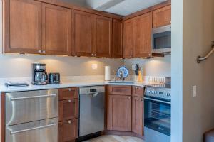 una cocina con armarios de madera y electrodomésticos de acero inoxidable en Villager Condo 1203 - Newly Remodeled and Resort Amenities en Sun Valley