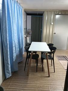 バンティングにあるInap Desa Hajah Yani, Kg Olak Lempitの青いカーテン付きの客室で、テーブルと椅子が備わります。