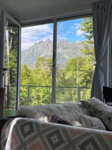 1 cama frente a una ventana grande con vistas en Casa moderna en el bosque y montaña en Villa La Angostura