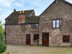 una antigua casa de piedra con puertas y ventanas rojas en The Granary en Woolaston