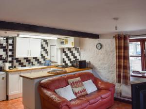 a living room with a leather couch in a kitchen at The Granary in Woolaston