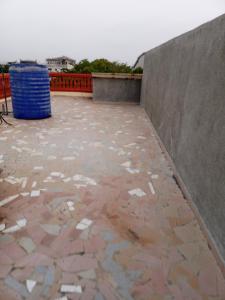 un patio con una pared y un cubo de basura azul en Studio privatif spacieux en air de plage, en Cotonou