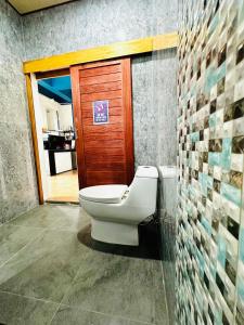 a bathroom with a toilet and a wooden door at The Scenery Beach Resort in Baan Khai