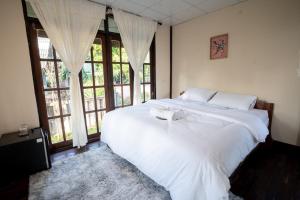 1 cama blanca grande en una habitación con ventanas en The woodshed village en Ban Ton Phung