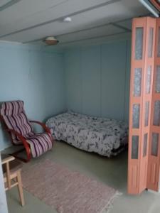 1 dormitorio con 1 cama y 1 silla en Talo rantasaunalla en Vaala