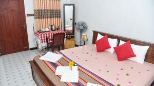 a bedroom with a bed with red and white pillows at Prem Nadee Hotel in Dambulla