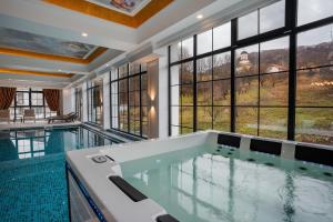 a large swimming pool in a house with windows at Hotel NOBLESSE Boutique&Spa in Râmnicu Vâlcea