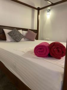 a bed with two red towels on top of it at Mirissa Gold Rush Villa in Mirissa