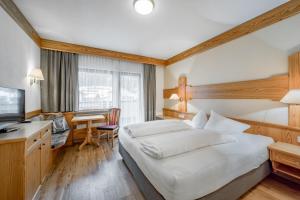 Habitación de hotel con cama, escritorio y TV. en Tilia living, en Ried im Oberinntal