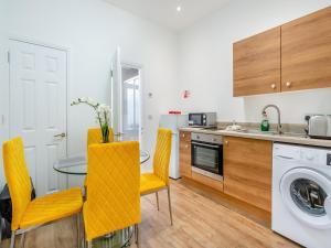 cocina con mesa y sillas amarillas en Apartment One - Uk44284, en Arbroath