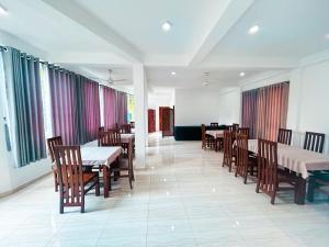 a dining room with tables and chairs and windows at Hotel Grand Resto in Katugastota