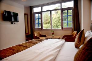 Una habitación de hotel con una cama y dos ventanas. en Pine Ville Shimla, en Shimla