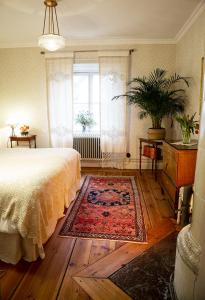 - une chambre avec un lit et un tapis sur du parquet dans l'établissement Långbro Gård i Mölnbo, à Mölnbo