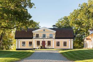 una grande casa bianca con tetto nero di Långbro Gård i Mölnbo a Mölnbo