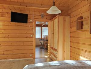 ザコパネにあるApartament Sosnaの木製の壁のベッドルーム、薄型テレビが備わります。