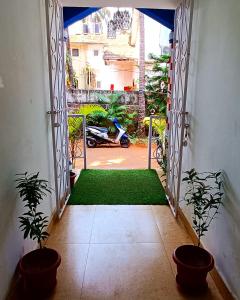 an open door to a yard with two potted plants at CASA SOMANJO INN in Calangute
