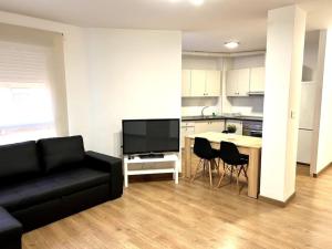 a living room with a black couch and a kitchen at La Merced - Más que apartamentos in Murcia