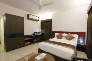 ein Hotelzimmer mit einem Bett und einem Schreibtisch mit einem Tisch in der Unterkunft Spring Hill Hotel & Apartments in Dhaka