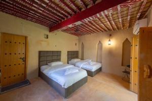 1 dormitorio con 2 camas en una habitación en بيت نُزل السلام Bait Salam inn, en Al Ḩamrāʼ