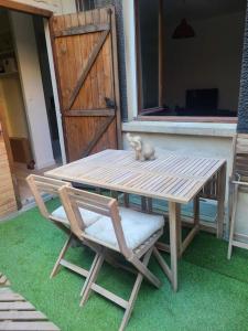 un chat assis sur une table à côté d'une chaise dans l'établissement Appartement au coeur de Ménilmontant, à Paris