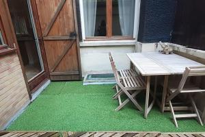 une table, deux chaises et un chat assis sur l'herbe dans l'établissement Appartement au coeur de Ménilmontant, à Paris