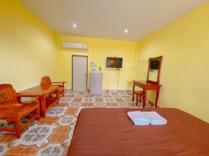 a room with a bed and a table and a refrigerator at โชติอนุสรณ์ รีสอร์ท ชุมพร in Ban Bang Mak (1)