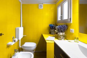 La salle de bains jaune est pourvue de toilettes et d'un lavabo. dans l'établissement Lussuoso Appartamento nel Cuore del Centro Storico, à Bologne