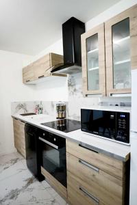 a kitchen with wooden cabinets and a black microwave at Appartement Le Moderne Idéal pour Couples et Professionnels in Ornans