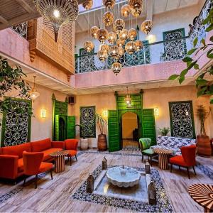 a living room with green doors and orange chairs at Riad contessa in Marrakech