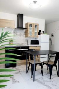 une cuisine avec une table noire et deux chaises dans l'établissement Appartement Le Moderne Idéal pour Couples et Professionnels, à Ornans