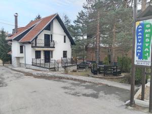 a white house with a picnic table in front of it at Apartmani - Mesko vajat in Divčibare