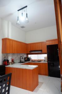 a kitchen with wooden cabinets and a black refrigerator at Bromo Venture in Probolinggo