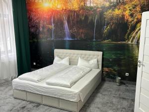 Bett in einem Zimmer mit einem Gemälde eines Wasserfalls in der Unterkunft Weißes Haus in Plauen